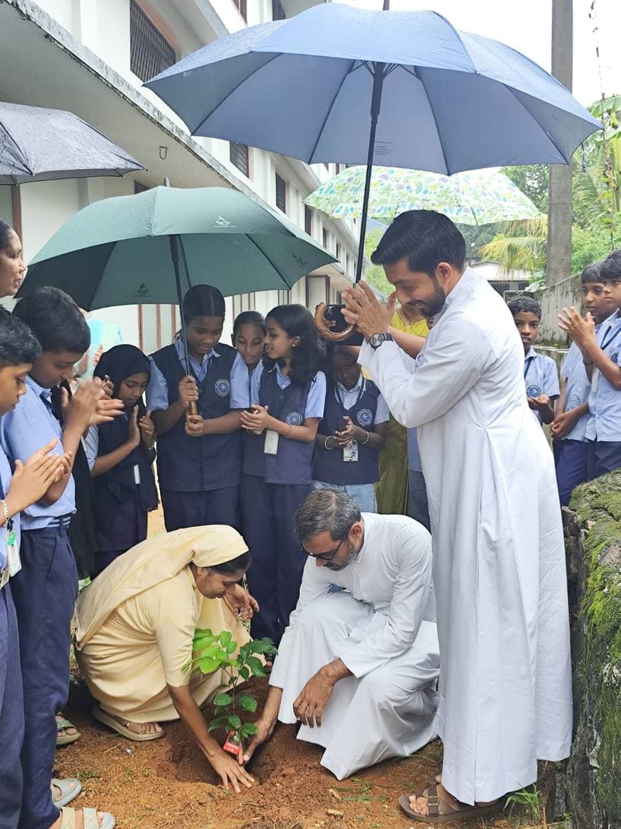 Students, teachers and clergy planting a sapling on the school grounds